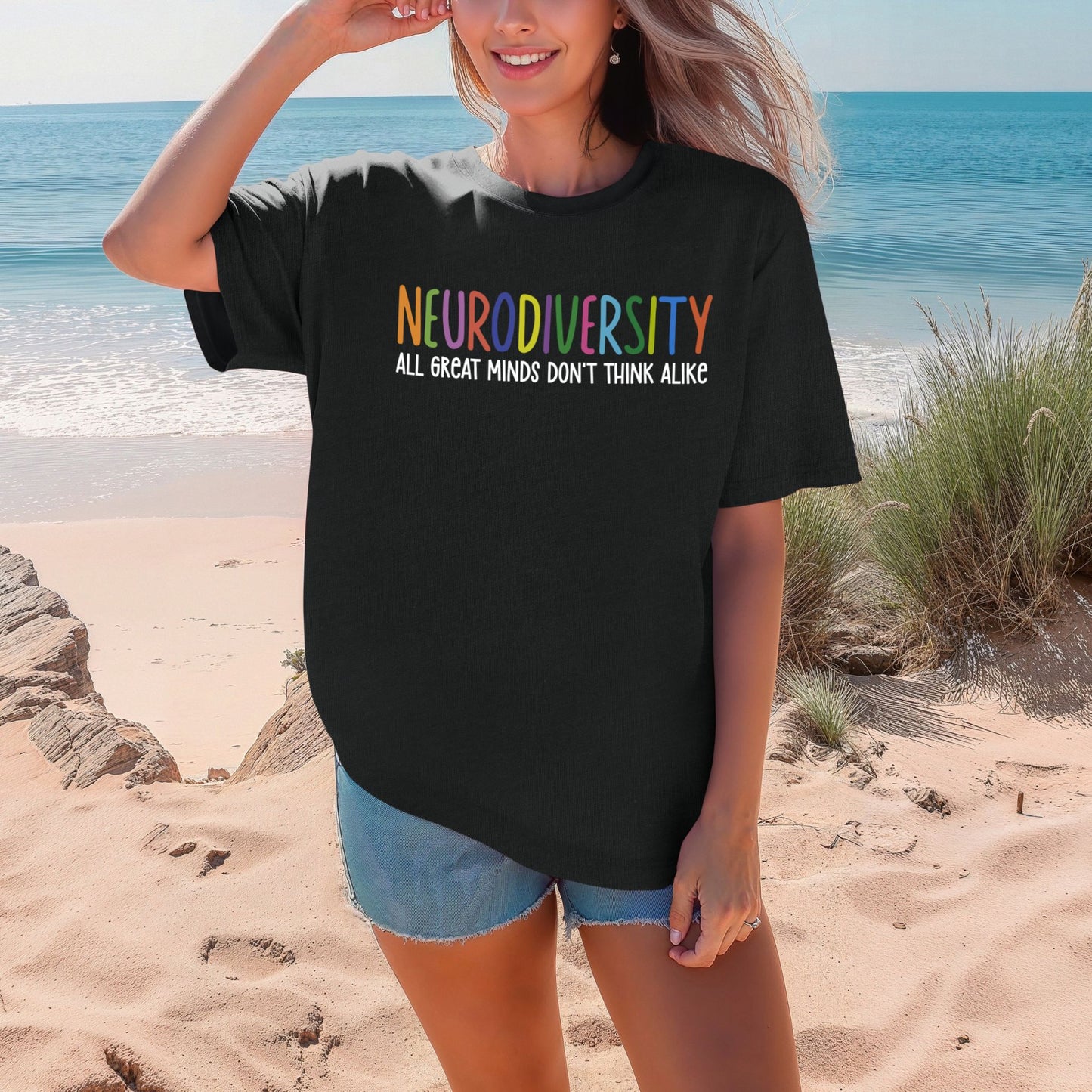 Person wearing a black t-shirt with 'NEURODIVERSITY ALL GREAT MINDS DON'T THINK ALIKE' text on a beach.