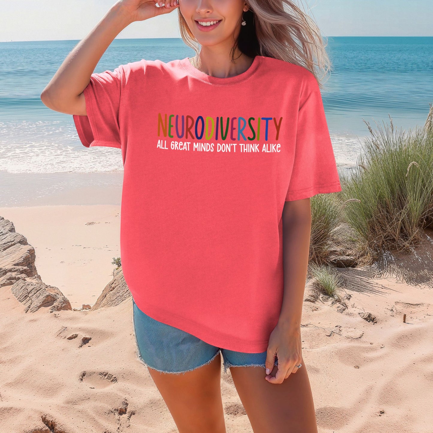 Person wearing a pink t-shirt with 'NEURODIVERSITY ALL GREAT MINDS DON'T THINK ALIKE' text on a beach.