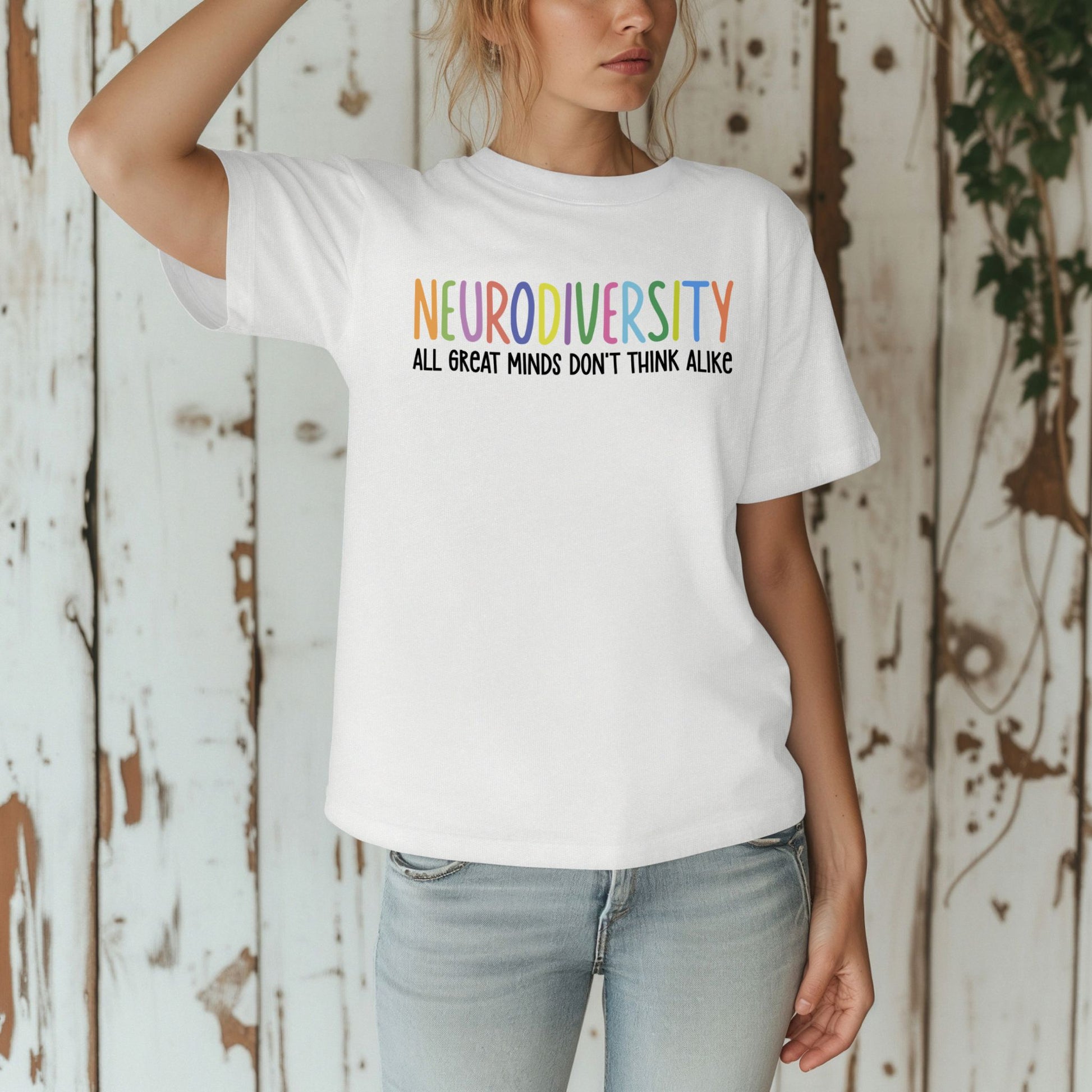 Person wearing a white t-shirt with 'NEURODIVERSITY ALL GREAT MINDS DON'T THINK ALIKE' text against a rustic wooden background.